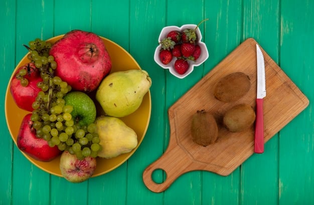 Close-up shot of various colorful fruits and vegetables, such as apples, carrots, sweet potatoes, and peas, laid out on a wooden cutting board. A knife is visible, ready to be used for chopping.