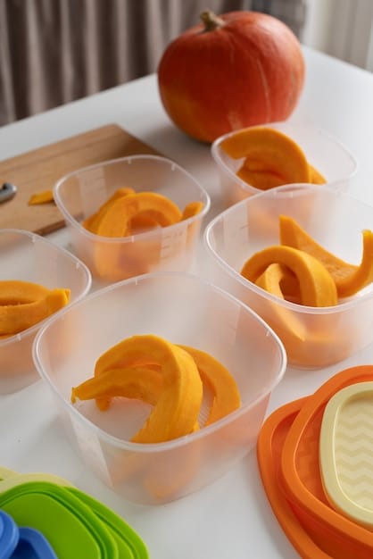 Close-up shot of a variety of pre-portioned healthy snacks neatly arranged in reusable containers. Examples include sliced apples with peanut butter, carrot sticks with hummus, and a small bag of trail mix.