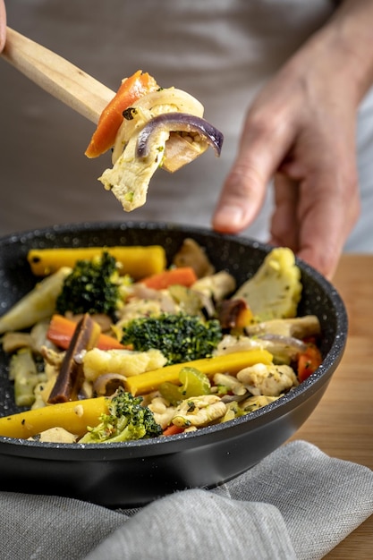 A close-up shot of a colorful and delicious stir-fry being cooked in a wok. The vegetables are vibrant and the sauce is glistening. The cook is stirring the ingredients with a wooden spoon.