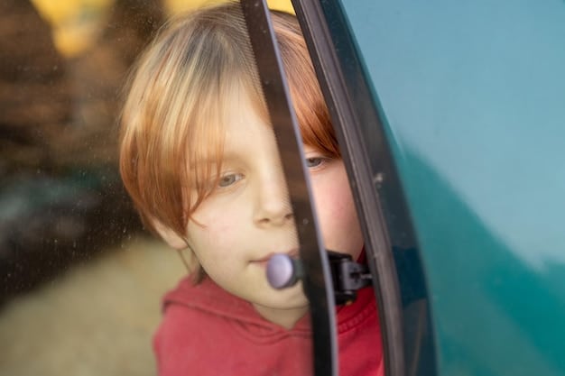 A close-up shot of a child in the back seat of a car, holding a microphone and singing enthusiastically. The focus is on the child's expression of pure joy and excitement. The car window is slightly blurred in the background.