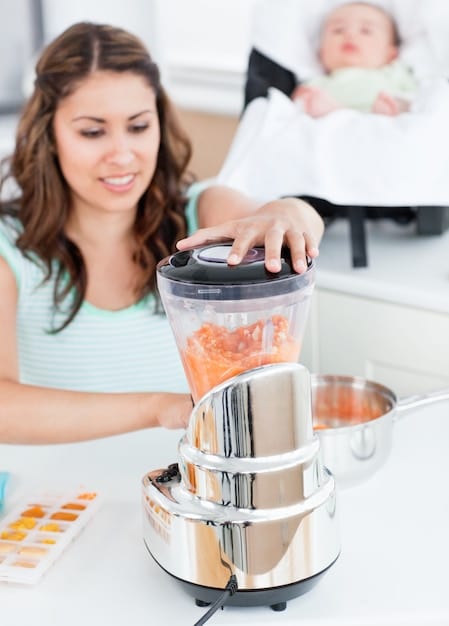 A mom using an immersion blender to puree cooked vegetables, with various containers and utensils laid out on the kitchen counter, highlighting the ease of operation.