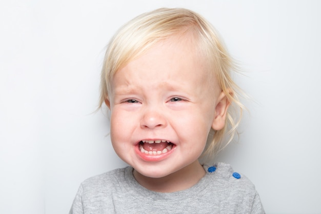 A close-up of a toddler's face contorted in a cry, tears streaming down their cheeks, mouth open wide in a scream.