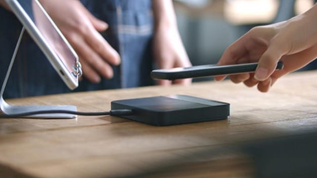 A pair of hands transferring files from a smartphone to an external hard drive using a USB cable. The background is a clean, minimalist desk with a laptop in the distance, creating a sense of focus and efficiency.