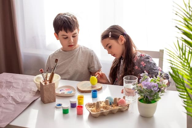 Two children are sitting at a table indoors, engaged in a craft activity. One is cutting construction paper with scissors, while the other is gluing googly eyes onto a cardboard tube. Their faces show concentration and enjoyment. Craft supplies surround them in a well-lit room.