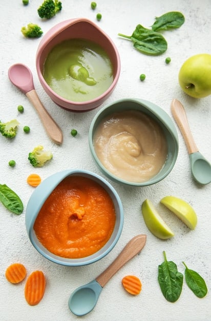 A colorful assortment of pureed vegetables and meats in small bowls, showcasing iron-rich food options for babies, such as spinach puree, beef puree, and lentil puree.