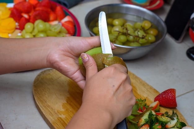 A parent carefully cutting a grape into quarters, demonstrating the correct method to reduce choking hazards for babies. The image is well-lit and focuses on the detail of the cutting action.