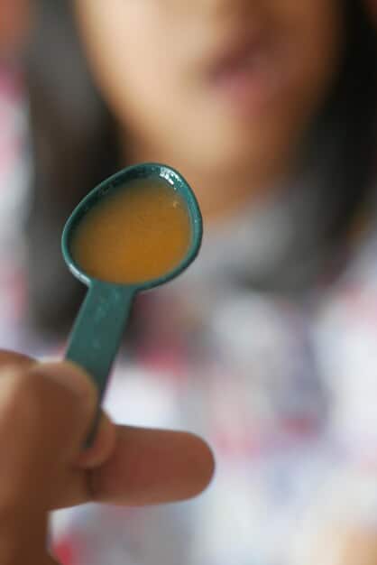 A parent carefully reading the ingredient label on the back of a baby food pouch, with a focus on highlighting sugar content and preservatives.