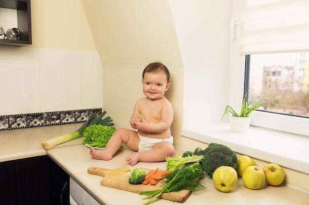 A baby sitting in a high chair, happily eating steamed broccoli florets with both hands. The background is a warmly lit dining room.