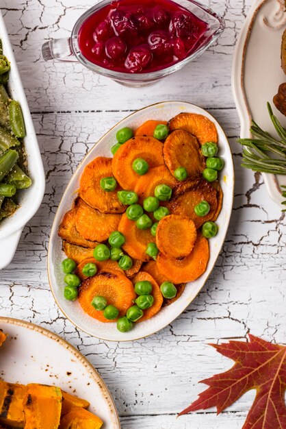 A close-up shot of various soft-cooked vegetables like carrot sticks, sweet potato wedges, and steamed green beans arranged on a plate. The vegetables are cut into thick, finger-friendly sizes suitable for a baby to hold.