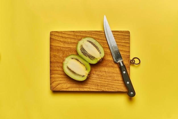 Three cut grapes next to a whole one, shown with a small knife for scale, illustrating the importance of cutting grapes into smaller, safer segments for babies. The background is a soft, blurred kitchen setting.