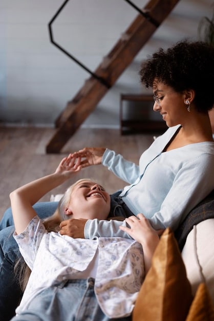 A mother smiling and relaxed while her partner plays with their children, showing shared responsibilities and the importance of support in managing parental duties.