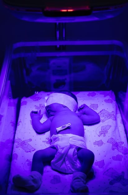 A serene baby sleeping soundly in a dark room with a white noise machine playing in the background