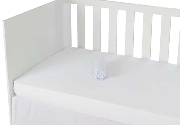 A close-up of a crib with a firm, flat mattress covered by a fitted sheet. There are no pillows, blankets, toys, or bumpers in the crib. The focus is on the simplicity and safety of the sleep environment.